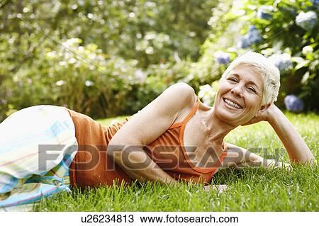 Portrait of a senior woman lying on grass and smiling View Large Photo Image Stock Image - Portrait of a senior woman lying on grass and smiling. Fotosearch