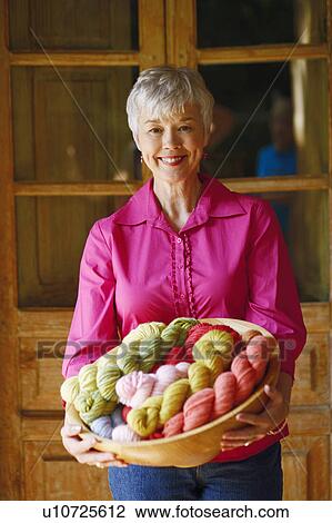 Portrait of a senior woman standing and holding a bowl of woolen balls View Large Photo Image Stock Image - Portrait of a senior woman standing and holding a bowl of woolen balls. Fotosearch