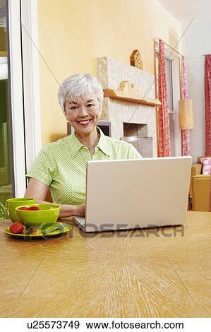 Stock Photo - Portrait of a senior woman using a laptop and smiling. Fotosearch