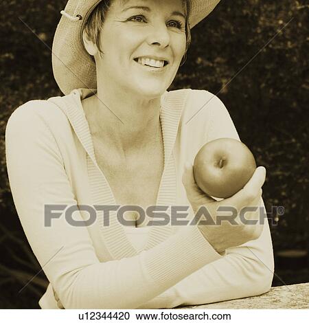 Close-up of a mature woman holding a granny smith apple View Large Photo Image Stock Image - Close-up of a mature woman holding a granny smith apple. Fotosearch