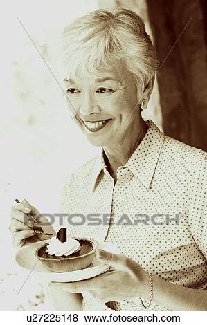 Stock Photo - Close-up of a senior woman eating a tart with a fork. Fotosearch
