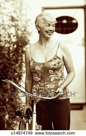 Stock Photo - Close-up of a senior woman standing with a bicycle. Fotosearch