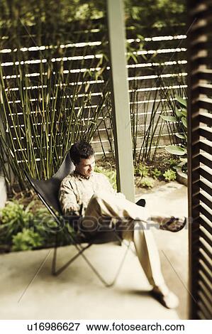 Stock Photo - High angle view of a mature man sitting on a chair. Fotosearch