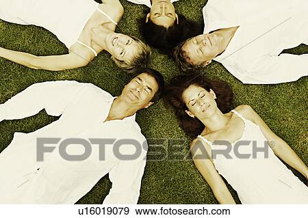 Stock Photo - High angle view of two mature men and three mature women lying on the grass. Fotosearch