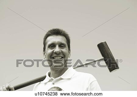 Stock Photo - Low angle view of a mature man holding a croquet mallet and a ball. Fotosearch