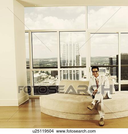 Portrait of a businessman sitting on a couch in an office View Large Photo Image Picture - Portrait of a businessman sitting on a couch in an office. Fotosearch