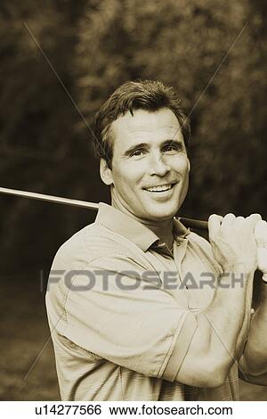 Stock Photograph - Portrait of a mature man holding a golf club and smiling. Fotosearch