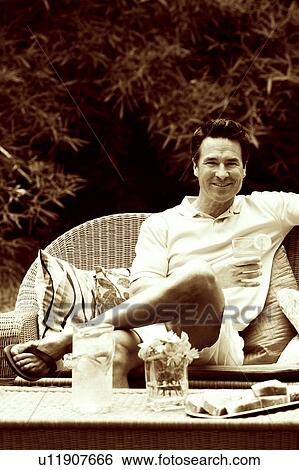 Portrait of a mature man sitting on a couch and holding a glass of lemonade View Large Photo Image Stock Photograph - Portrait of a mature man sitting on a couch and holding a glass of lemonade. Fotosearch