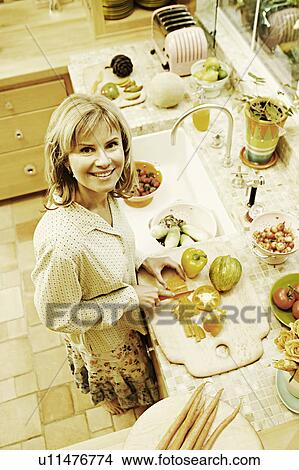 Portrait of a mature woman cutting yellow bell peppers in the kitchen View Large Photo Image Picture - Portrait of a mature woman cutting yellow bell peppers in the kitchen. Fotosearch