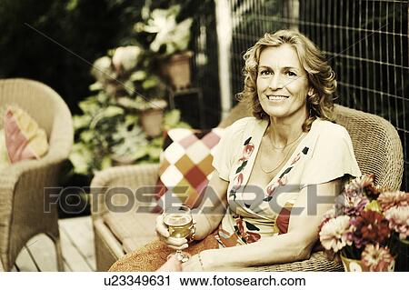 Stock Image - Portrait of a mature woman holding a glass of wine and smiling. Fotosearch