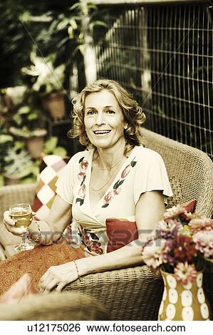 Portrait of a mature woman holding a glass of wine and smiling View Large Photo Image Stock Photograph - Portrait of a mature woman holding a glass of wine and smiling. Fotosearch