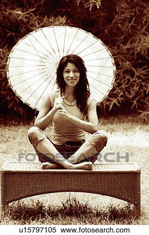 Stock Photography - Portrait of a mature woman holding a parasol and smiling. Fotosearch
