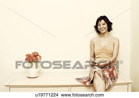 Picture - Portrait of a mature woman operating a personal data assistant and smiling. Fotosearch