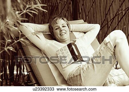 Stock Image - Portrait of a mature woman reclining on a lounge chair. Fotosearch