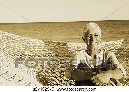 Portrait of a mature woman sitting in a hammock and smiling View Large Photo Image Stock Photo - Portrait of a mature woman sitting in a hammock and smiling. Fotosearch