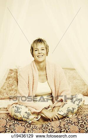 Portrait of a mature woman sitting on the bed View Large Photo Image Stock Photo - Portrait of a mature woman sitting on the bed. Fotosearch