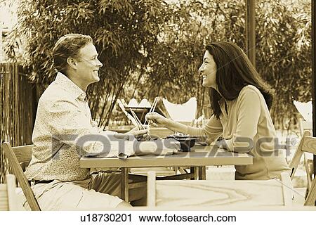 Stock Image - Side profile of a mature couple sitting at a table in a restaurant. Fotosearch