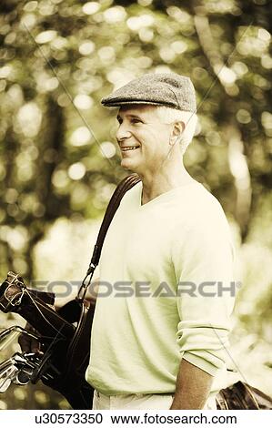 Side profile of a mature man carrying a golf bag and smiling View Large Photo Image Stock Image - Side profile of a mature man carrying a golf bag and smiling. Fotosearch