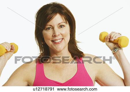 Portrait of a mature woman holding dumbbells and smiling View Large Photo Image Stock Image - Portrait of a mature woman holding dumbbells and smiling. Fotosearch