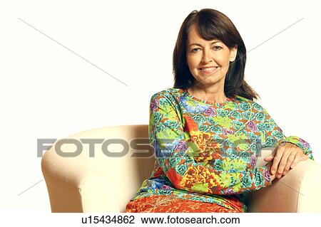 Portrait of a mature woman sitting in an armchair and smiling View Large Photo Image Stock Image - Portrait of a mature woman sitting in an armchair and smiling. Fotosearch