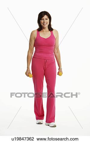Stock Image - Portrait of a mature woman standing and holding dumbbells. Fotosearch