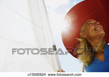Low angle view of a mature woman smiling in a sailboat View Large Photo Image Picture - Low angle view of a mature woman smiling in a sailboat. Fotosearch