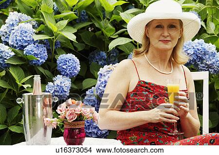 Portrait of a mature woman holding a glass of juice View Large Photo Image Picture - Portrait of a mature woman holding a glass of juice. Fotosearch