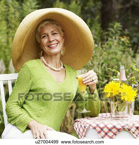 Stock Photo - Portrait of a senior woman sitting on a chair holding a glass of juice. Fotosearch