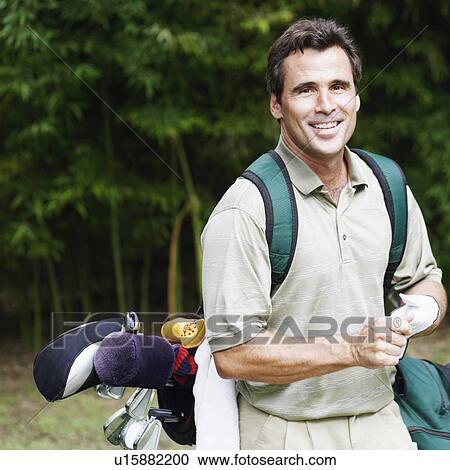 Stock Image - Close-up of a mature man carrying a golf bag. Fotosearch