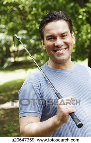 Stock Photo - Close-up of a mature man holding a golf club and smiling. Fotosearch