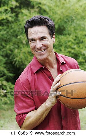 Stock Photo - Close-up of a mature man holding a basketball. Fotosearch