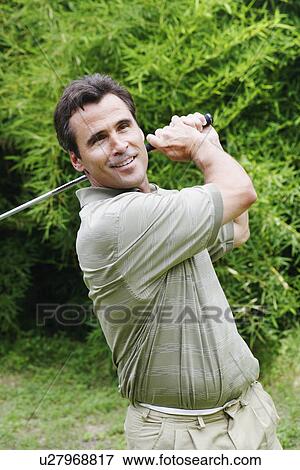 Stock Photo - Close-up of a mature man swinging a golf club. Fotosearch