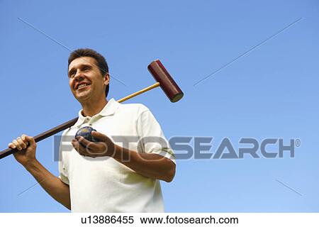 Low angle view of a mature man holding a croquet mallet and a ball View Large Photo Image Stock Photography - Low angle view of a mature man holding a croquet mallet and a ball. Fotosearch