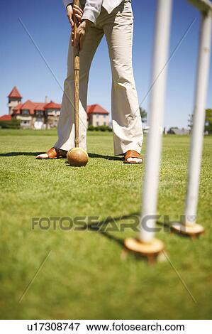 Stock Photo - Low section view of a woman playing croquet in a field. Fotosearch