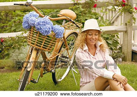 Mature woman sitting beside a bicycle View Large Photo Image Stock Image - Mature woman sitting beside a bicycle. Fotosearch