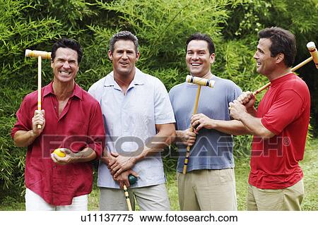 Stock Photography - Mid adult man with three mature men holding croquet mallets and balls. Fotosearch