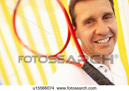 Portrait of a mature man holding a tennis racket and smiling View Large Photo Image Picture - Portrait of a mature man holding a tennis racket and smiling. Fotosearch