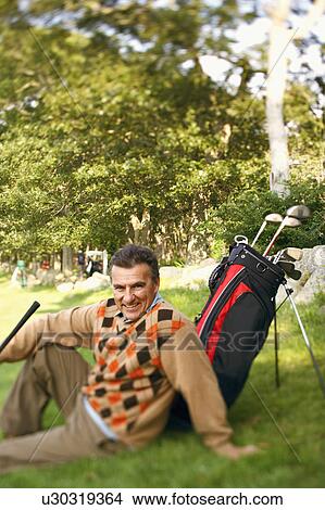 Picture - Portrait of a mature man sitting near a golf bag. Fotosearch
