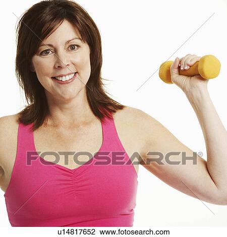 Stock Image - Portrait of a mature woman holding a dumbbell and smiling. Fotosearch