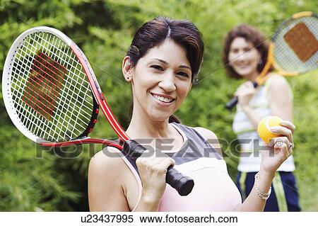 Portrait of a mature woman holding a tennis ball and a tennis racket with another mature woman standing behind her View Large Photo Image Stock Photography - Portrait of a mature woman holding a tennis ball and a tennis racket with another mature woman standing behind her. Fotosearch