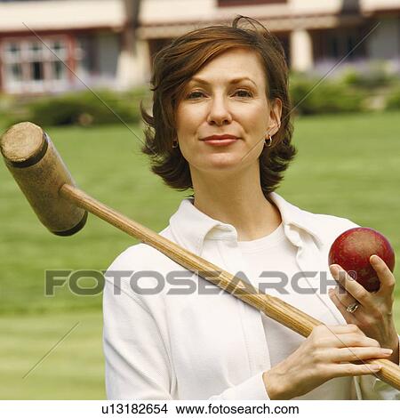 Picture - Portrait of a mid adult woman holding a croquet mallet and a ball. Fotosearch