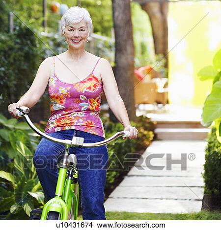 Picture - Portrait of a senior woman standing with a bicycle. Fotosearch