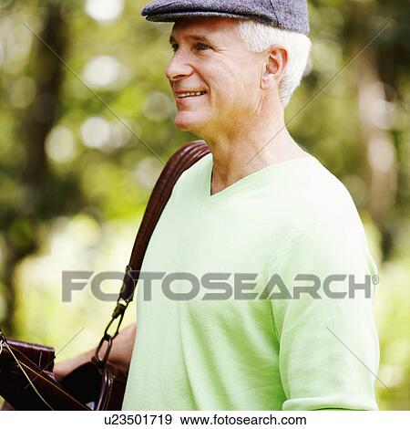 Stock Photo - Side profile of a mature man carrying a golf bag and smiling. Fotosearch