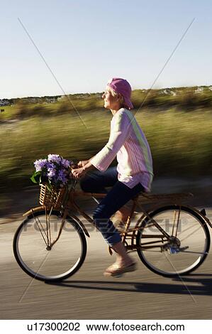 Stock Image - Side profile of a mature woman riding a bicycle. Fotosearch