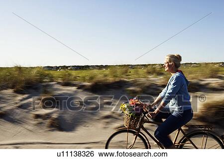 Stock Photograph - Side profile of a mature woman riding a bicycle. Fotosearch