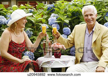 Close-up of a mature couple toasting glasses of juice View Large Photo Image Stock Image - Close-up of a mature couple toasting glasses of juice. Fotosearch