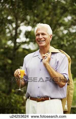 Picture - Close-up of a mature man holding a glass of juice. Fotosearch