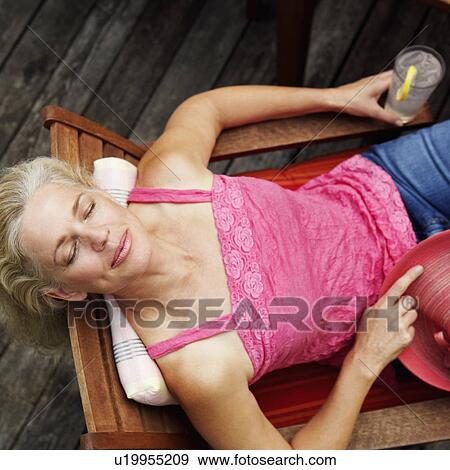 High angle view of a mature woman reclining in an armchair and holding a glass of lemon juice View Large Photo Image Stock Photo - High angle view of a mature woman reclining in an armchair and holding a glass of lemon juice. Fotosearch