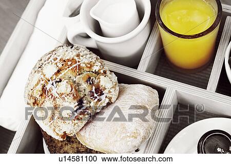 Stock Image - High angle view of muffins and a glass of orange juice in a breakfast tray. Fotosearch