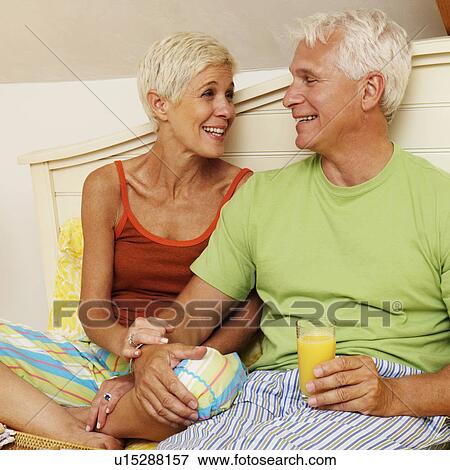 mature man and a senior woman sitting on the bed and smiling View Large Photo Image Stock Photo - mature man and a senior woman sitting on the bed and smiling. Fotosearch